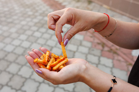 Woman's hand holds crackers, snack and fast food concept. Selective focus on hands with blurred background and copy space for text.の写真素材