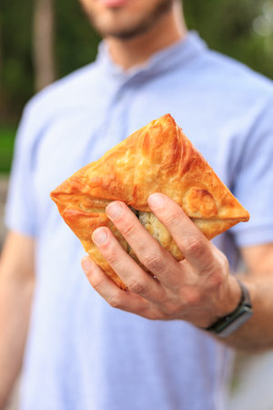 Vertical frame of hands holding pastries, fast food snack concept. Background with selective focus and copy space for textの写真素材