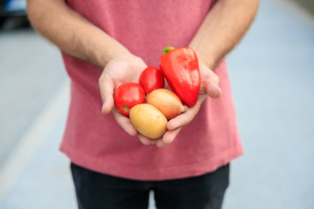 The guy's hand holds vegetables. Selective focus on hands with blurred background and copy space for text.の写真素材
