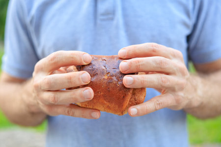 A man holds a pastry, fast food or snack in his hands