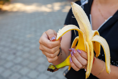 Woman's hand holding bananas, snack and fast food concept. Selective focus on hands with blurred background and copy space for text.の写真素材