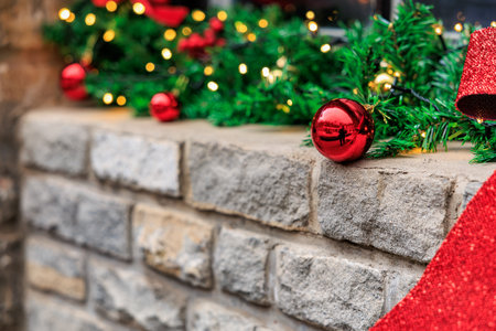 Festive christmas decoration with red ornaments and green garland on stone wall.の写真素材