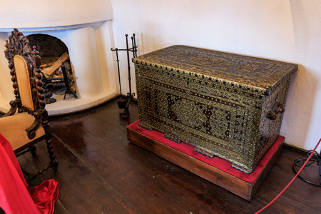 Antique ornate chest in historical room with wooden floor and fireplace.