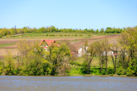 Scenic riverside landscape with farmhouses and greenery.の写真素材