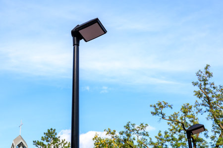 A street light is lit up in the daytime. The sky is clear and blue. The light is on a poleの写真素材
