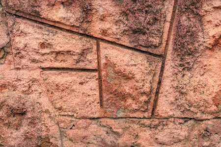 Textured brick wall with geometric patterns in earthy tones.の写真素材