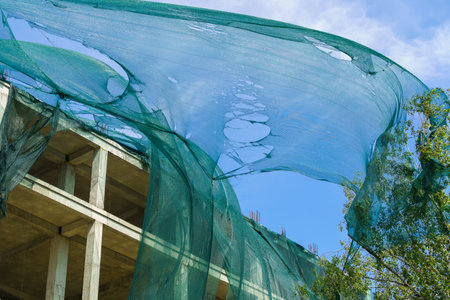 Protective mesh on scaffolding torn by hurricane wind. Background with selective focus and copy space for text.の写真素材