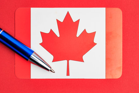 Canadian flag with blue pen on red background.の写真素材