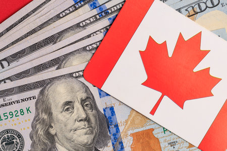 Canadian flag on card with american dollar bills background.の写真素材