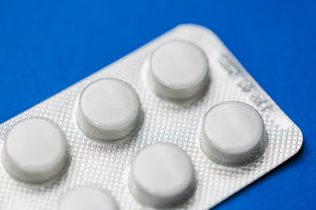 Close-up of blister pack with white tablets on blue background.