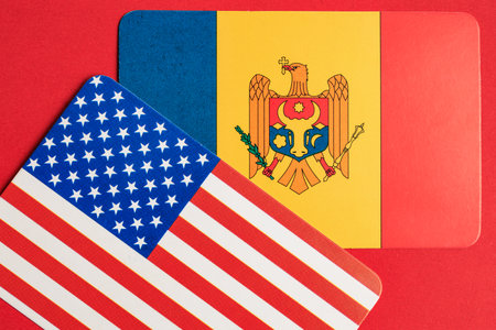 Flags of united states and moldova on vibrant red background symbolizing international relations.