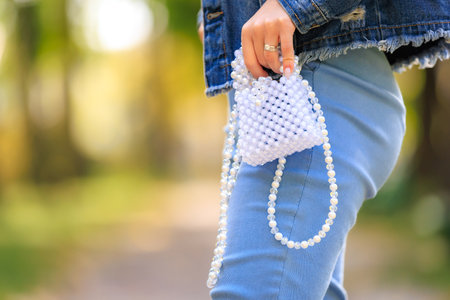 A stylish handbag in the hands of a young woman. Background with selective focus and copy space for textの写真素材