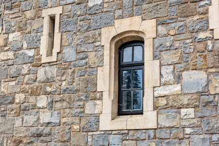 Historic stone castle wall with arched window and rustic architecture.