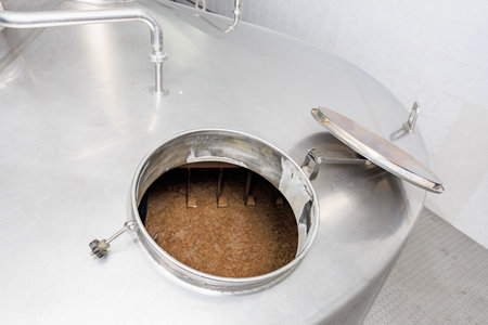 Brewery equipment with open stainless steel fermentation tank in use.の写真素材
