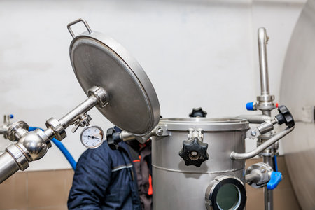 Industrial brewing equipment with worker adjusting stainless steel fermentation tank.の写真素材