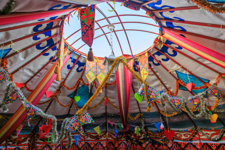 A colorful tent with a large round opening in the center. The tent is decorated with many colorful flags and banners.の写真素材