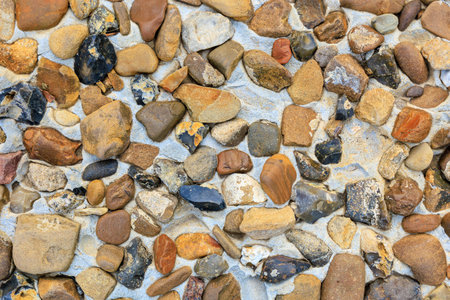 A pile of rocks on a white surface. The rocks are of various sizes and colors, creating a textured...