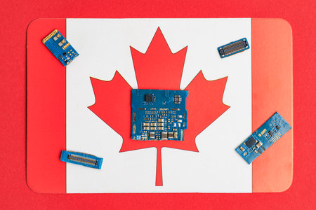 Electronic circuit boards on canadian flag background.