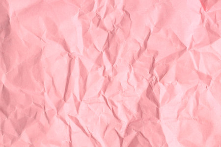 Crumpled pink paper texture with wrinkled surface and soft hue.の写真素材
