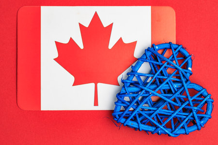 Canadian flag with blue heart woven decoration on red background.の写真素材