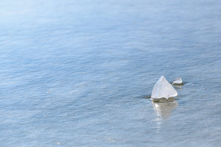 Serene frozen lake with ice chunks on calm surface.
