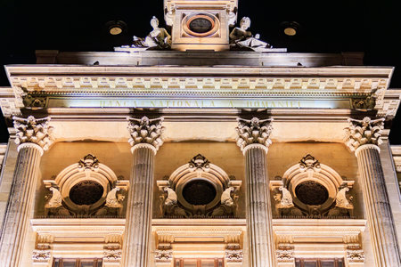 Illuminated facade of National Bank of Romania, inscription in Romanian, at night with architectural details.の写真素材