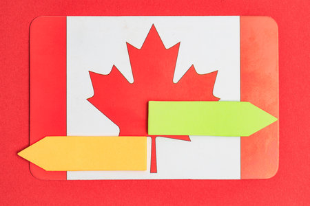 Canadian flag with red maple leaf and colored arrows on red background.の写真素材