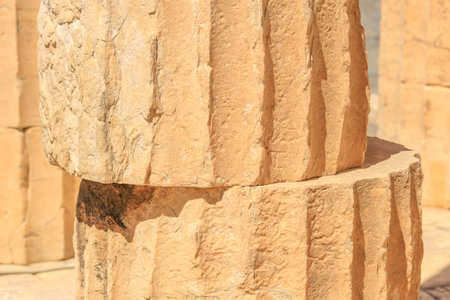 Two large stone pillars with a rough texture and a weathered appearance. The pillars are stacked on...