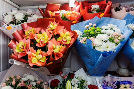 A display of flowers in a store with a blue and white polka dot wrapping. The flowers are arranged in various bunches and are of different colors
