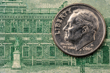 A silver coin with the word Liberty on it is sitting on a green piece of paper. The paper has a...