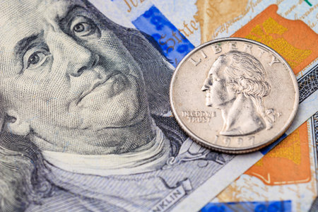 A silver coin with the word Liberty on it sits on top of a stack of green and yellow billsの写真素材