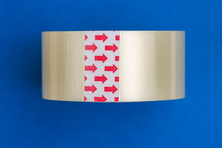 Transparent adhesive tape with red arrows on blue background.の写真素材