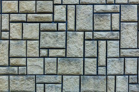 Patterned stone wall with rectangular blocks and blue mortar.
