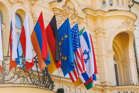 International flags displayed on historic european building facade.の写真素材