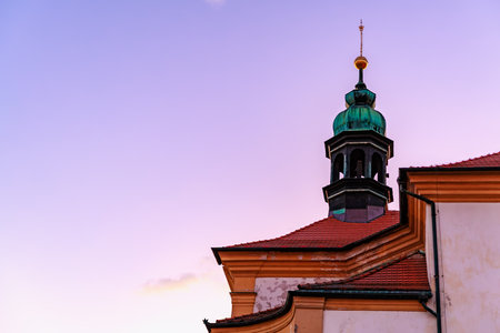 Sunset over historic church with red roof and copper steeple.