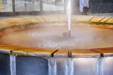 Circular fountain with water spray in urban setting.