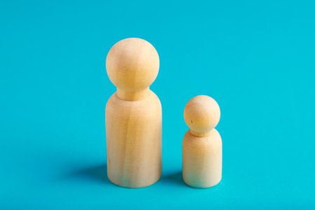 Wooden peg dolls on blue background: large and small figures.の写真素材
