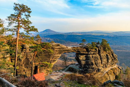 Majestic rock arch with scenic mountain view and lush forest landscape.の写真素材
