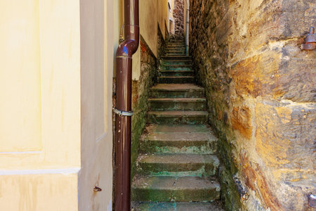 Narrow stone alleyway with steep stairs between old buildings.の写真素材