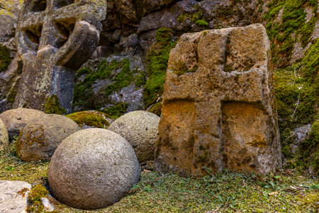 Ancient stone crosses and spherical rocks in mossy forest setting.の写真素材