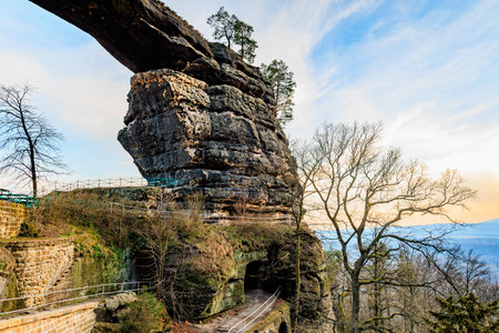 Majestic sandstone arch formation surrounded by trees at sunset.の写真素材