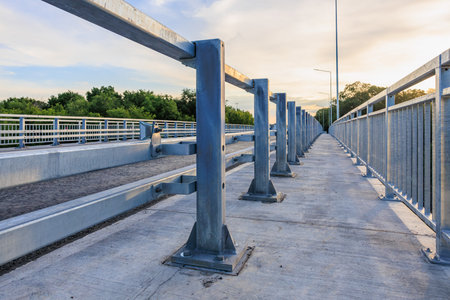 Modern steel bridge in scenic park setting with sunset sky.の写真素材