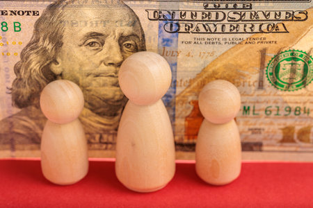 Wooden figures in front of us currency featuring benjamin franklin.の写真素材