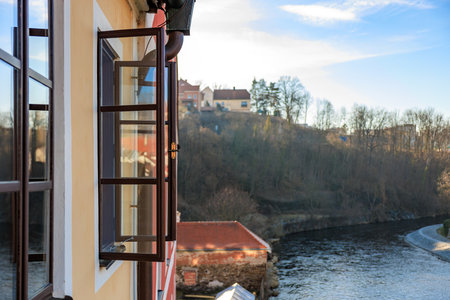 A window with a view of a river and a house. The window is open and the view is of a beautiful landscapeの写真素材