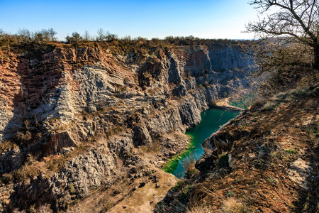 Stunning canyon with turquoise lake and rocky cliffs under clear blue sky.の写真素材