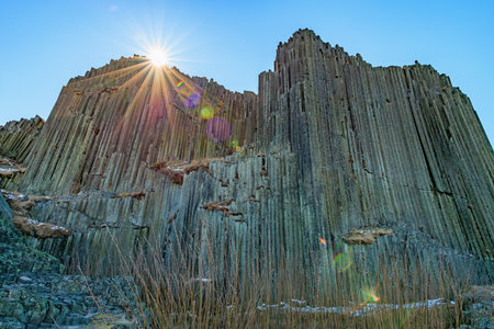 Spectacular sunlit columnar basalt cliffs with clear blue sky.