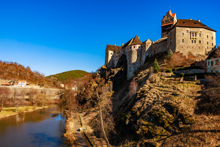 Historic medieval castle overlooking river under clear blue sky.の写真素材