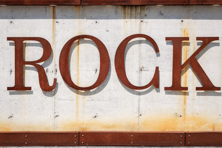 Rusty metal letters spelling rock on weathered concrete background.の写真素材
