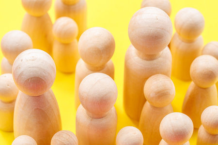 Wooden figurines on vibrant yellow background.の写真素材