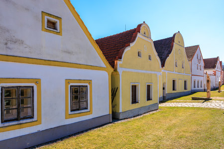 Traditional czech baroque village houses with yellow facades and red roofs on a sunny day.の写真素材